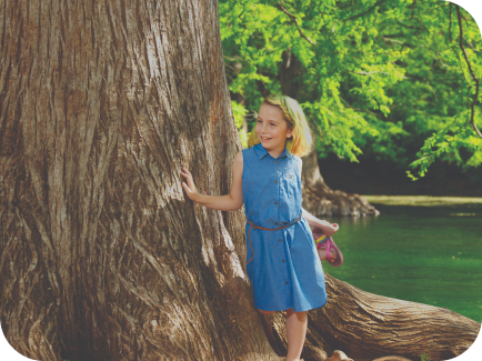 Cera, a real CRYSVITA patient, standing next to a tree